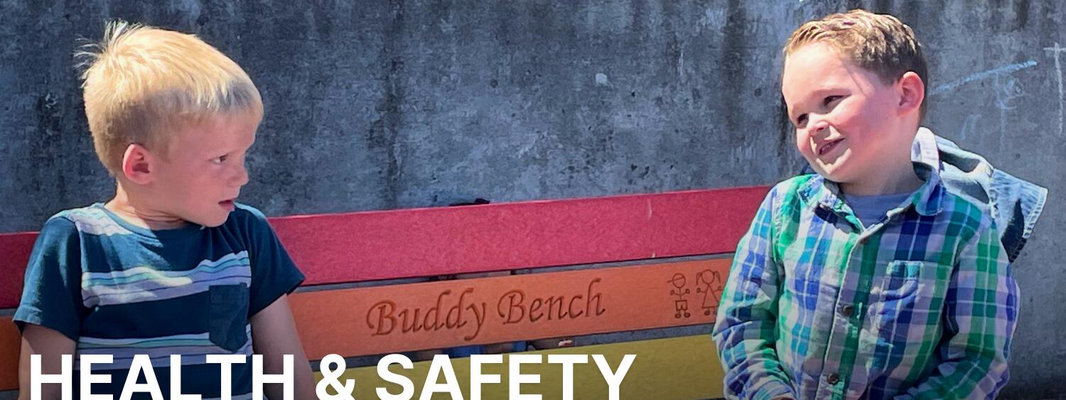 Health & Safety banner photo of two young students sitting on the buddy bench